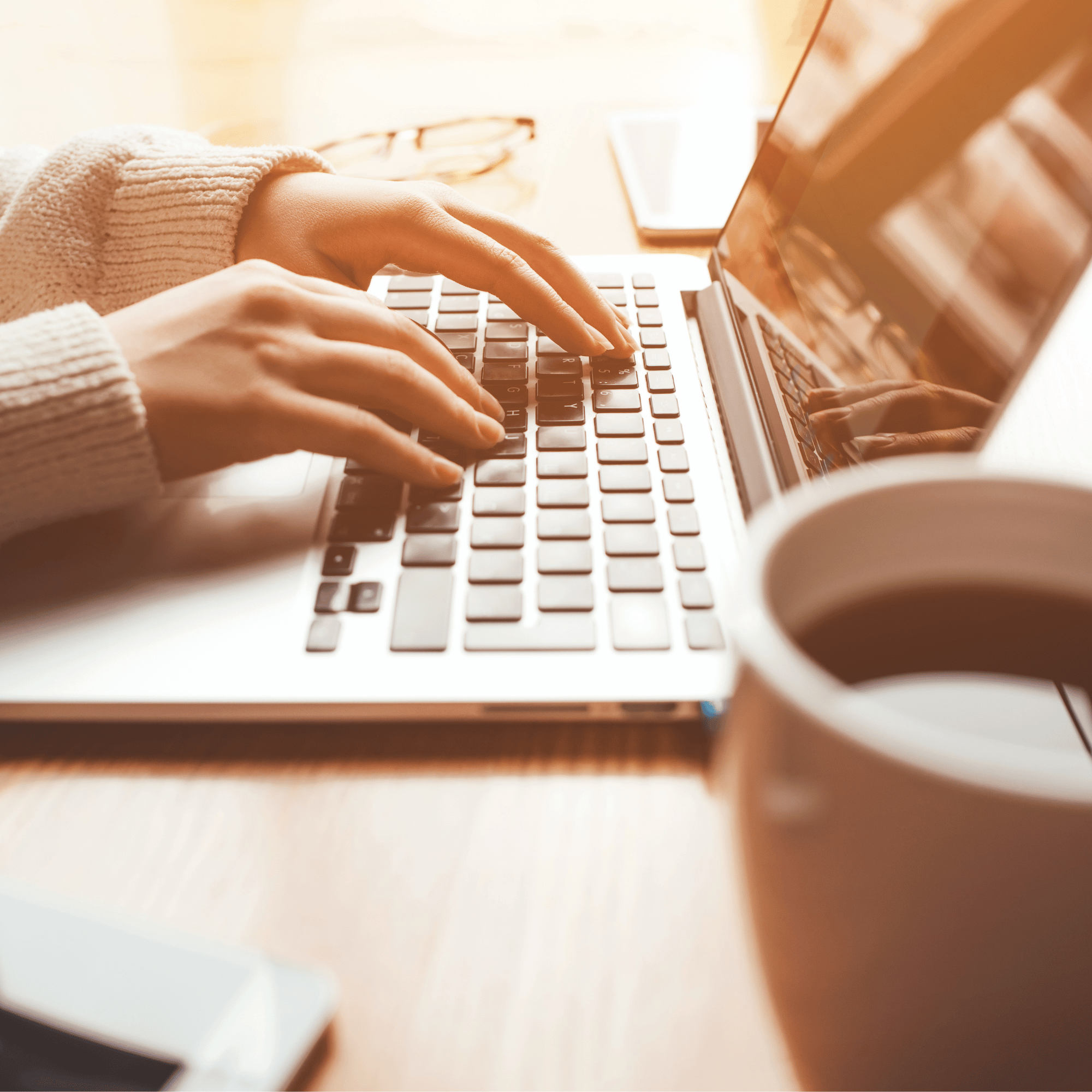 woman on her laptop with a cup of coffee and her phone